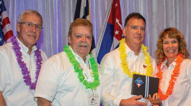 3 men and a woman wearing leis receiving squadron of the year award